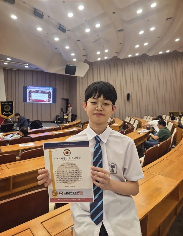 Mark holding his Challenge Korea Awards certificate in the National Assembly auditorium