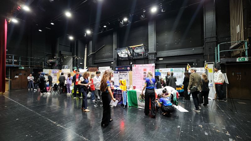 Students presenting projects at an exhibition on a dark theatre stage