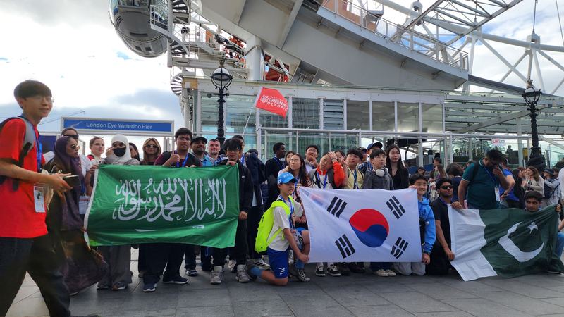 Students holding the flags of Saudi Arabia, South Korea and Pakistan by the London Eye