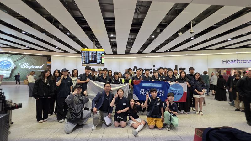 The delegation posing with banners in the Heathrow arrivals hall