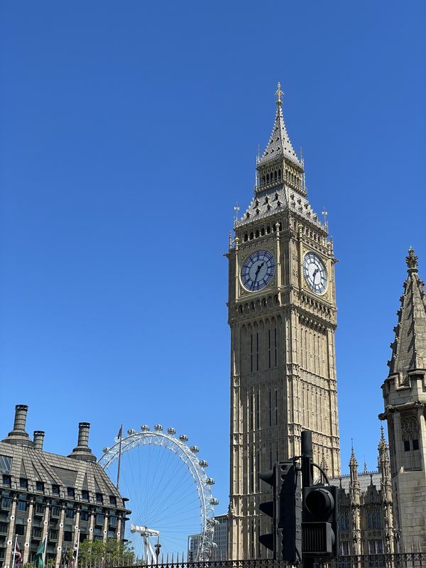 Big Ben against a clear blue sky with the London Eye behind